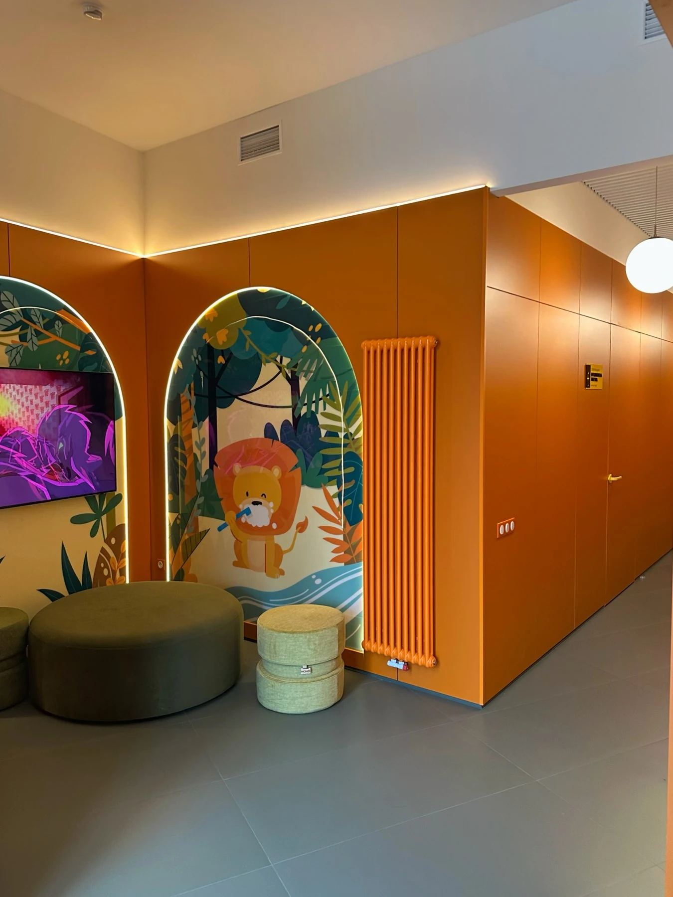Зона очікування INNOVO Kids з м’якими пуфами, теплими кольорами та левчиком на стіні
